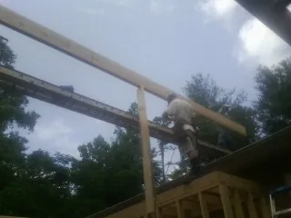 Carpenter setting a ridge beam over a new addition frame — Ice Dam Removal by Roofing Brothers in Athena