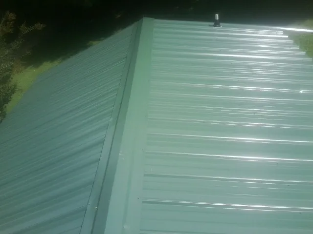 New green metal panels meeting at the ridge of a roof — Flat Roof Repair work by our crew in Athena