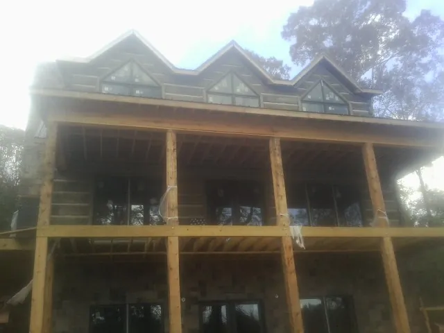 Dormers and porch framing on a large log home under construction — Roof Coating work by our crew in Athena