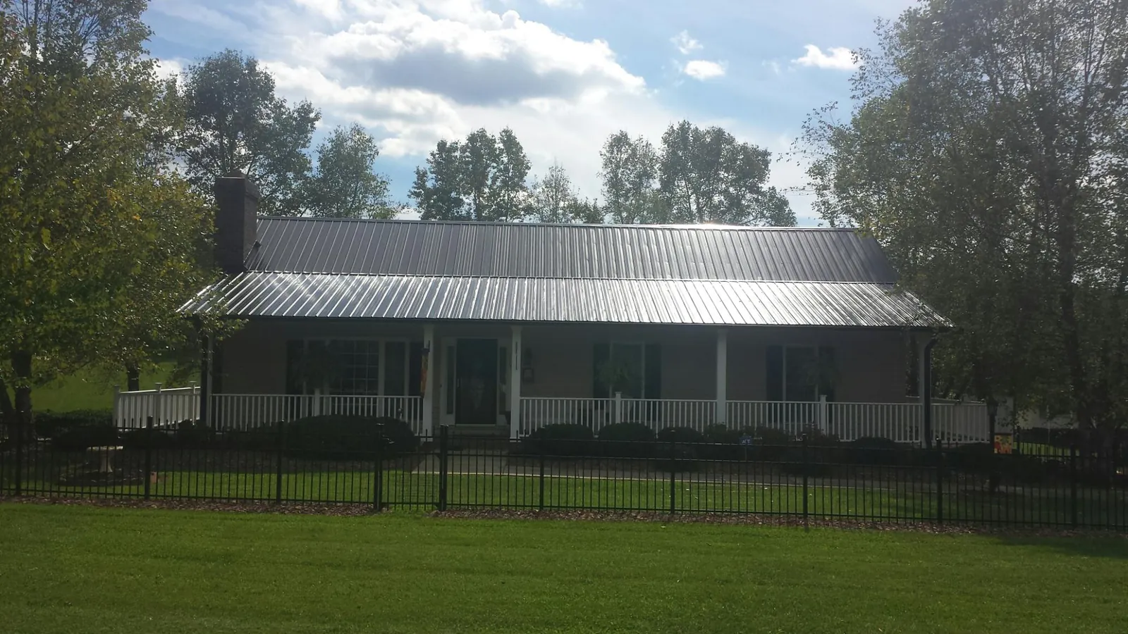 Gray metal roof on a brick ranch with a full width front porch — Gutter Guard Installation work by our crew in Athena